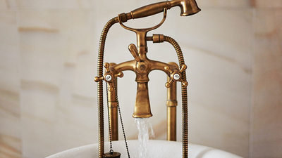 Water running down from antique bronze faucet tap into the bathtub. Indoors, stylish interior, copy space.