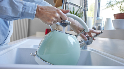 Close Up Of Woman Carefully Filling Kettle From Tap And Saving Water