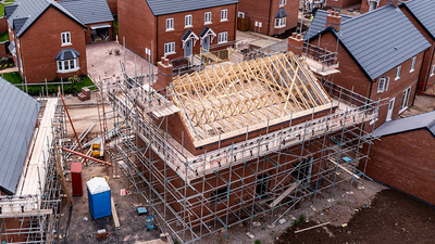 An aerial view of new build homes on a new housing estate with the roof exposed and wooden rafters and beams showing.